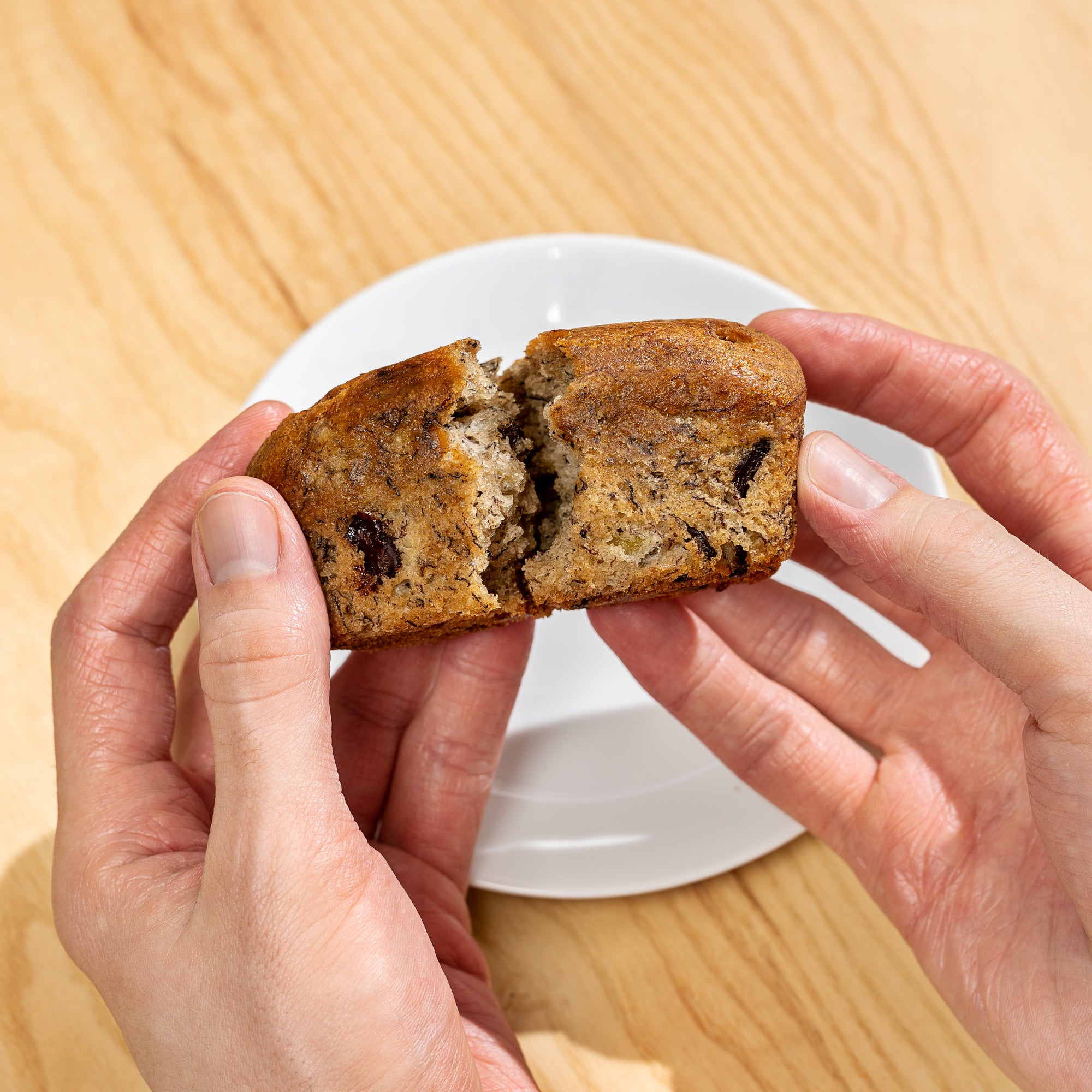 Banana bread being broken in half. 